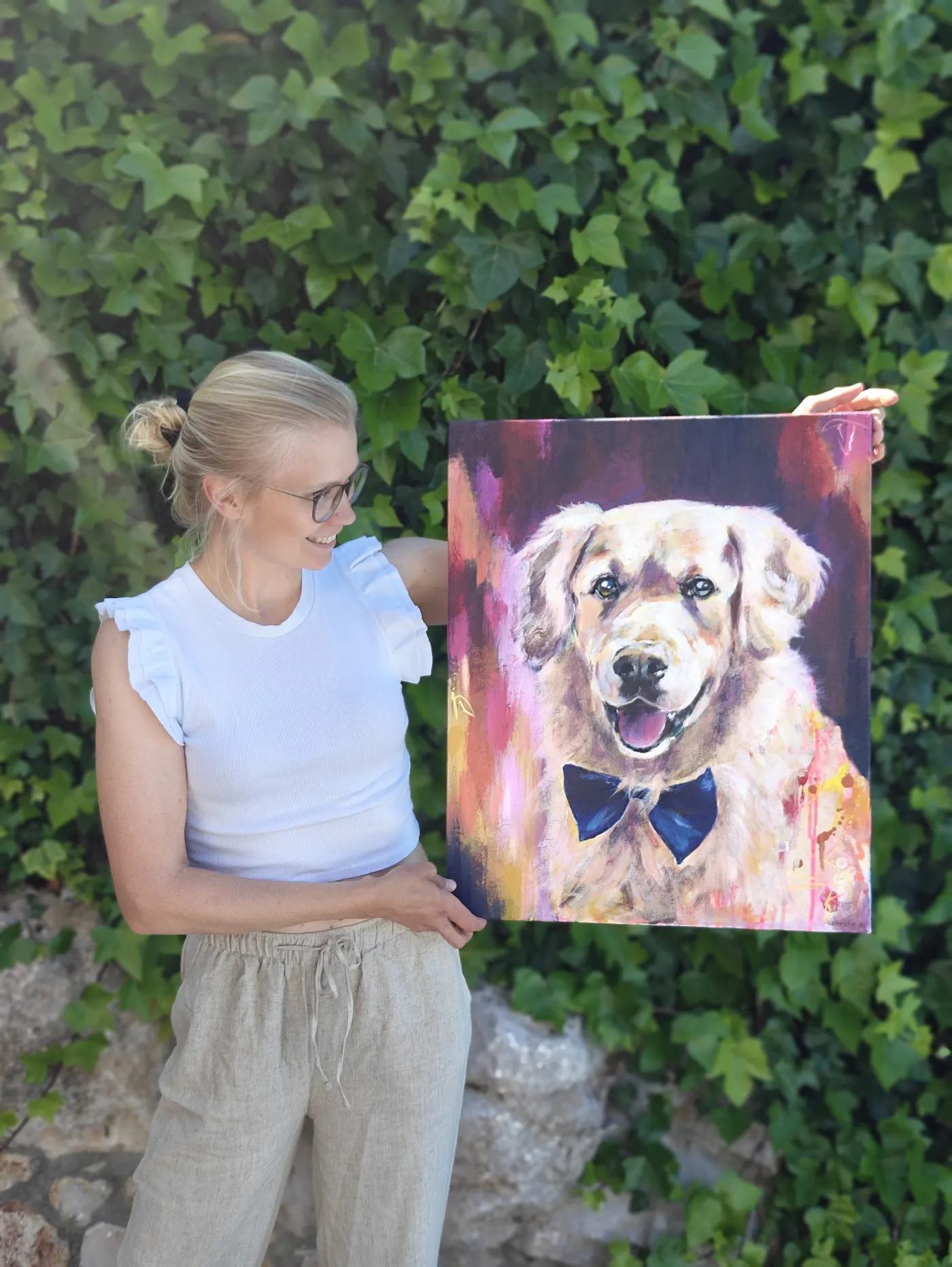 Emma-Sofia holding a custom dog painting outdoors